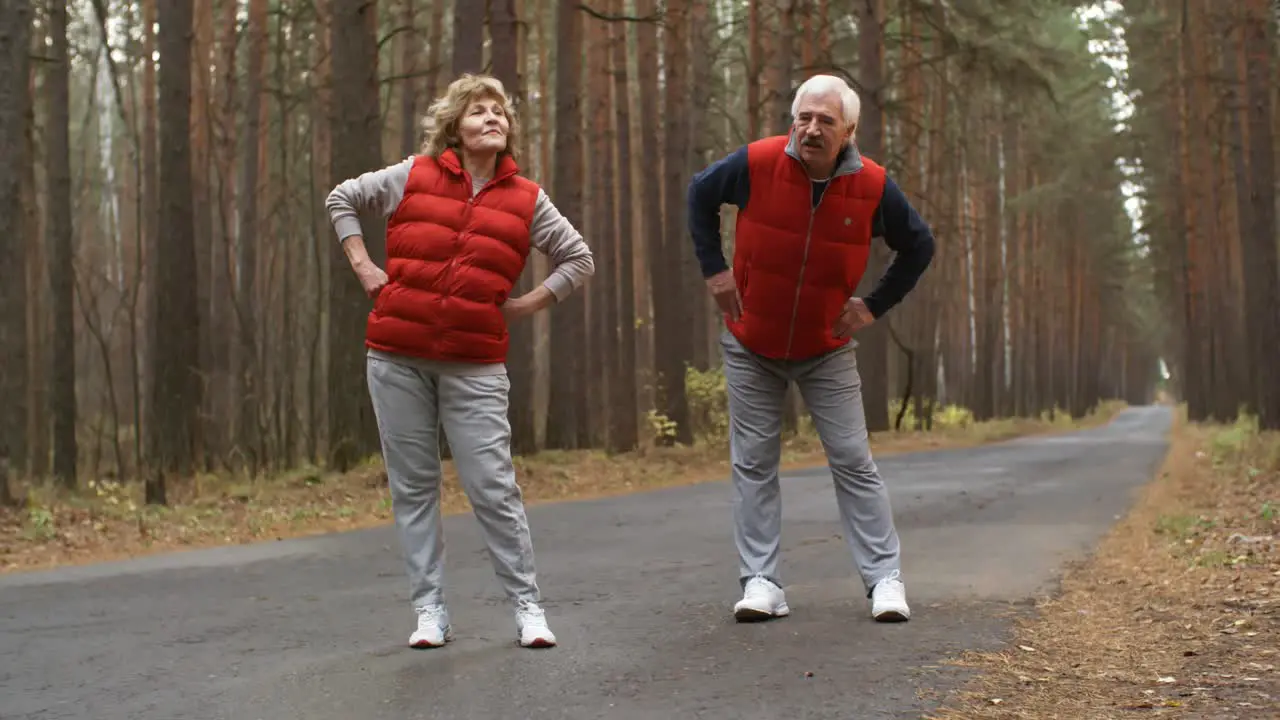 Senior Couple Chatting And Stretching Together In The Forest