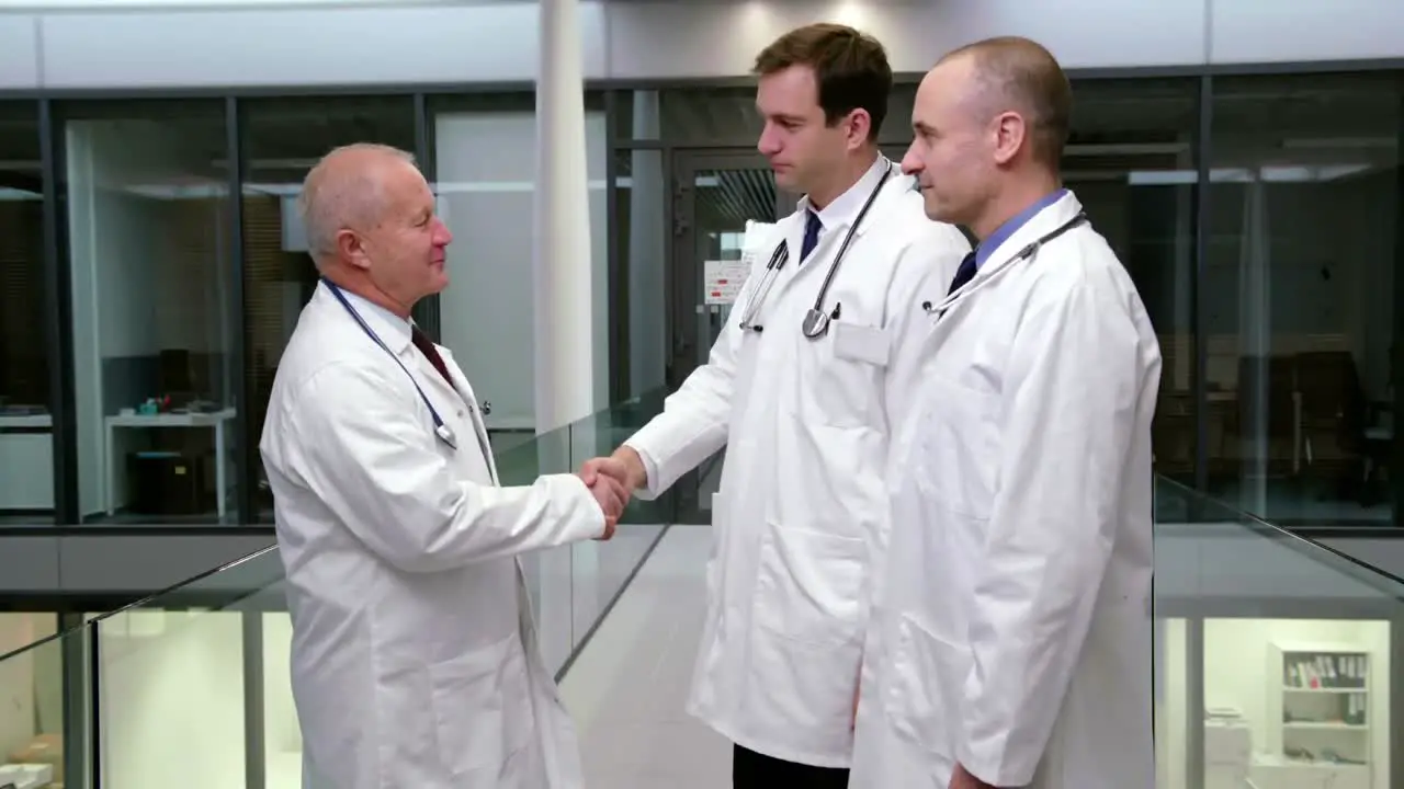 Doctors interacting with each other while shaking hands in corridor