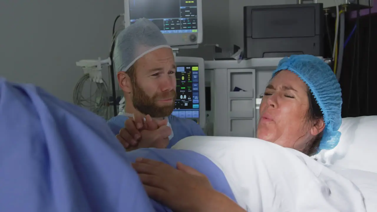 Front view of Caucasian man comforting pregnant woman during labor in operation theater at hospital 