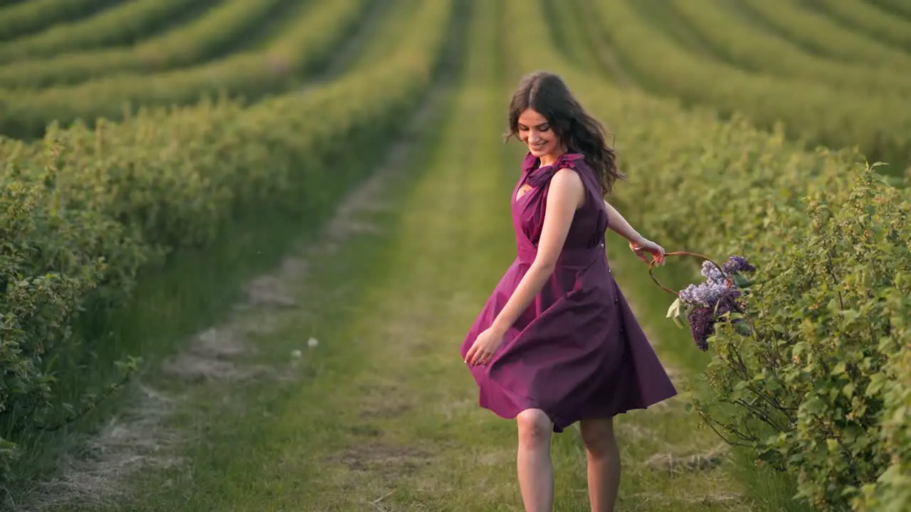 Beautiful attractive girl in a purple dress with a basket of lilac flowers