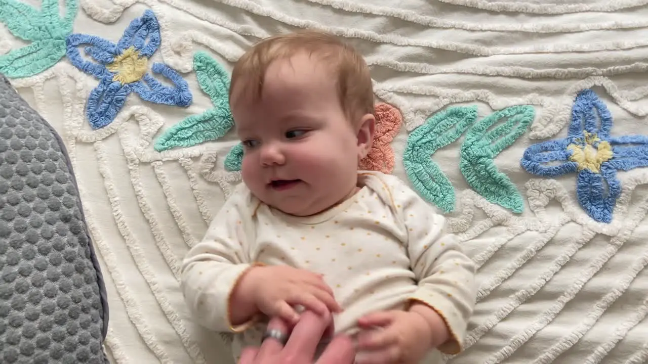 Happy cute young baby girl smiling while being tickled by her parent