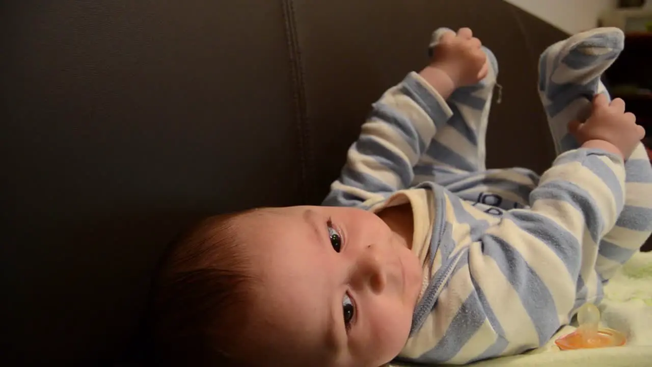 Close up overhead shot of baby boy on the soffa playing with his feet