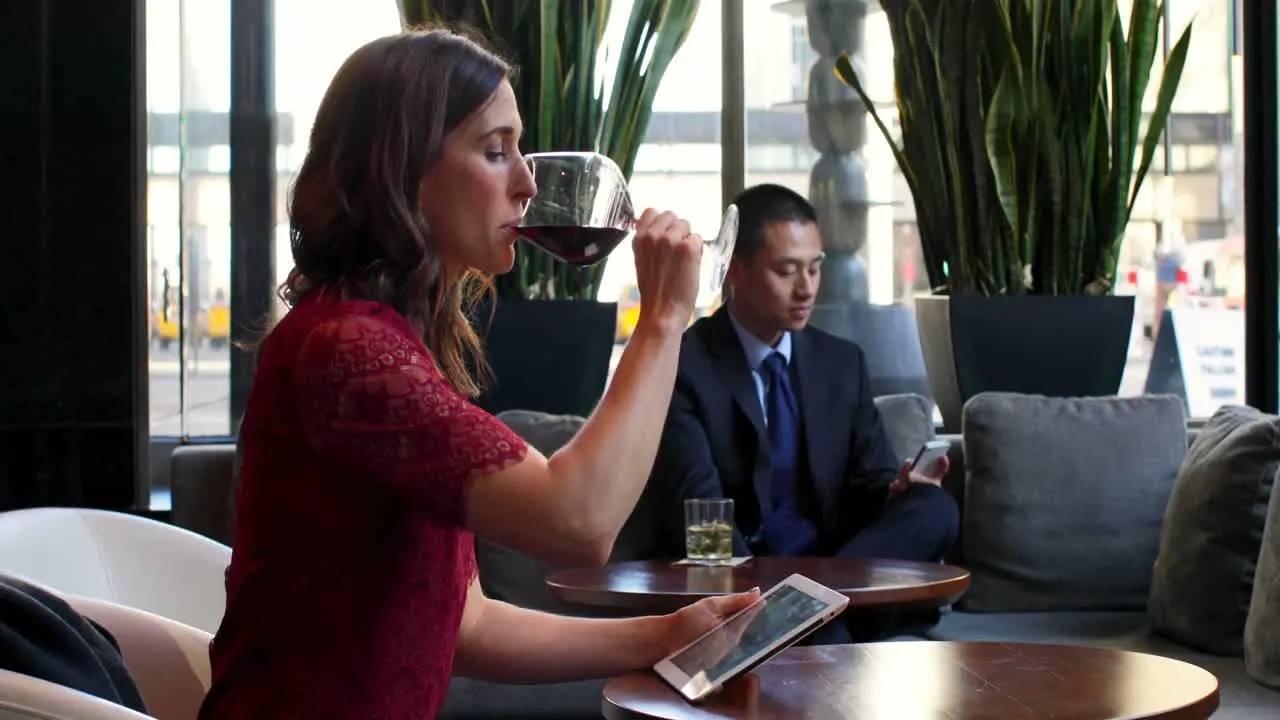 Businesswoman using digital tablet while having red wine in hotel 4k