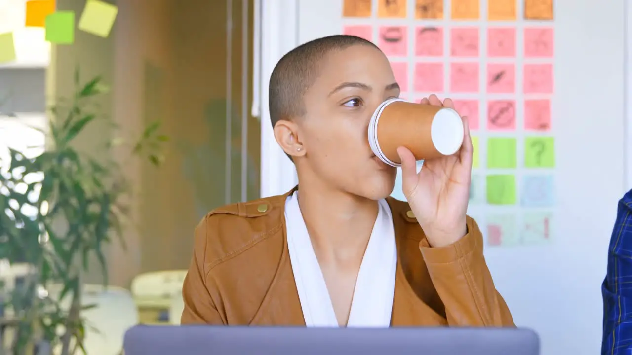 Front view of young caucasian female executive having coffee at desk in modern office 4k