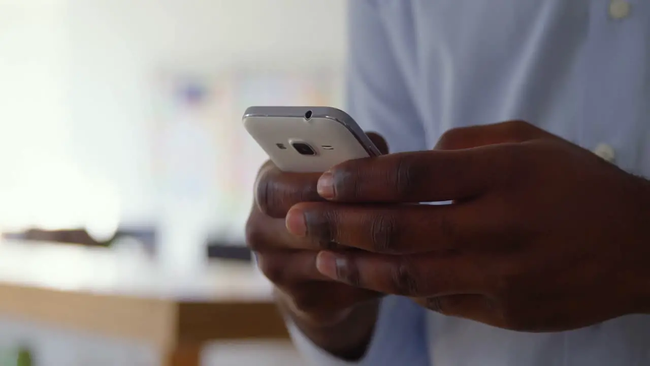 Close-up of young black businessman working on smartphone in a modern office 4k