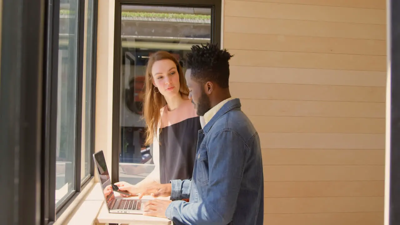 Side view of young mixed-race business team planning and standing near window of modern office 4k