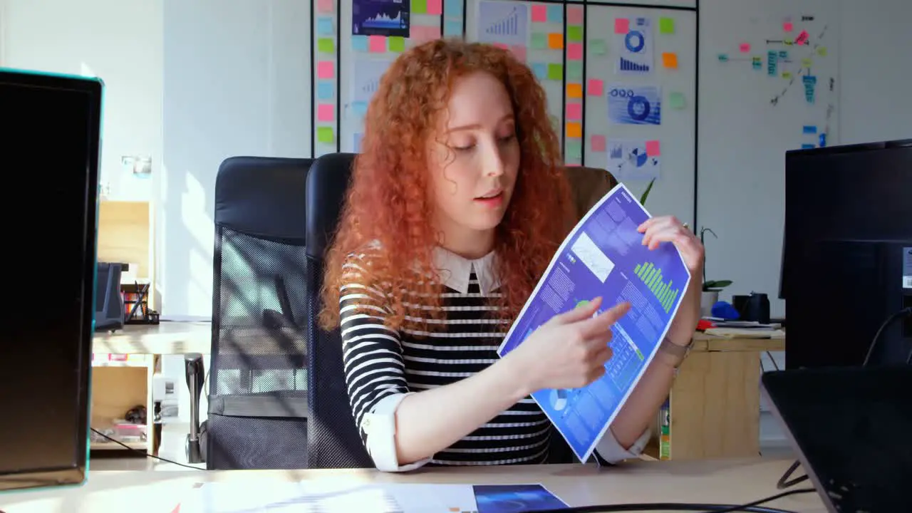 Front view of young cool caucasian businesswoman sitting at desk and looking at camera in office 4k