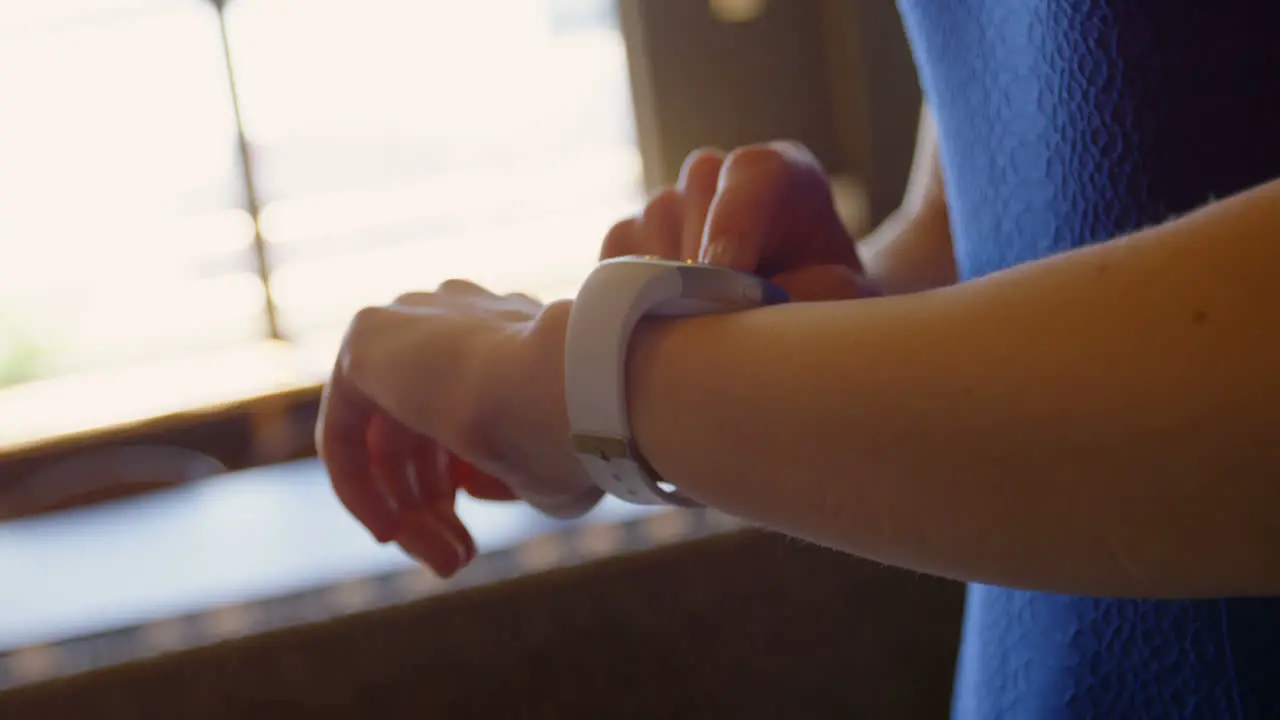 Close-up of young businesswoman checking her smartwatch and using mobile phone in a modern office 4k