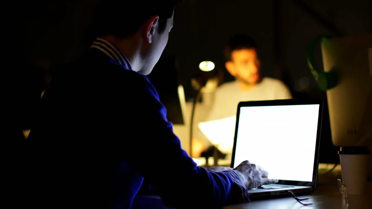 Male executive using laptop at desk in office 4k