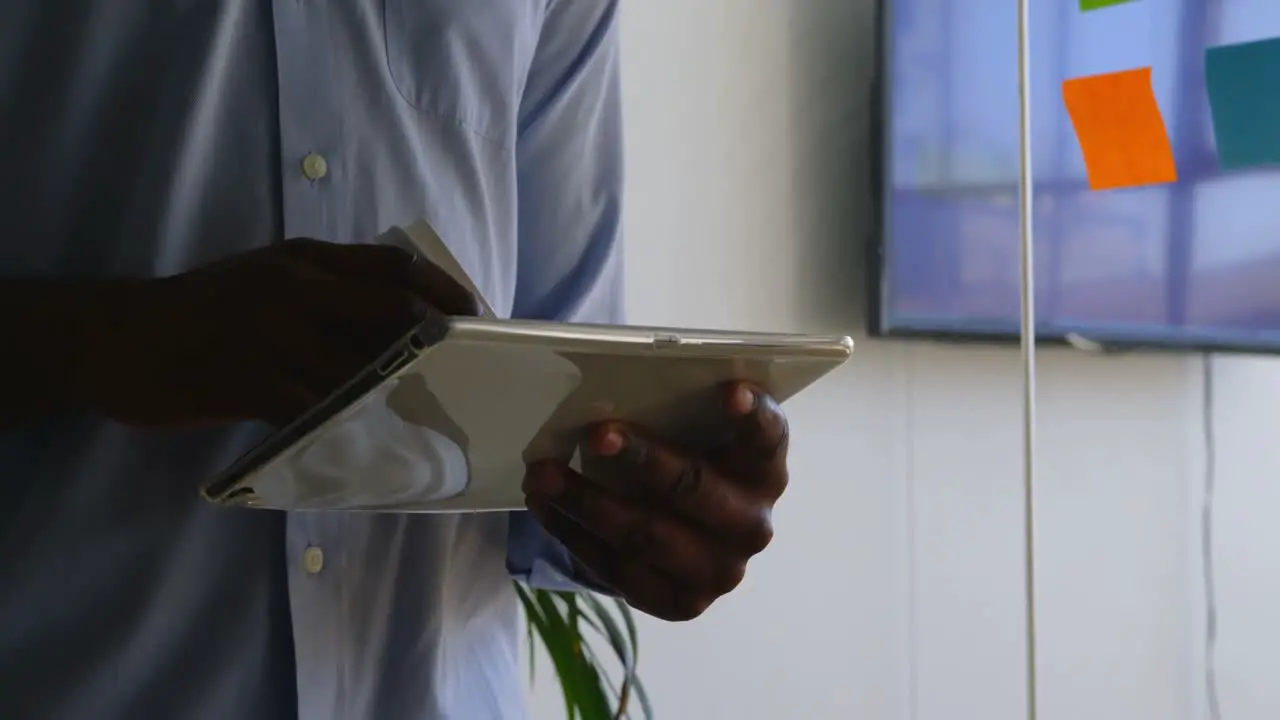 Mid section of young black businessman working on digital tablet in a modern office 4k