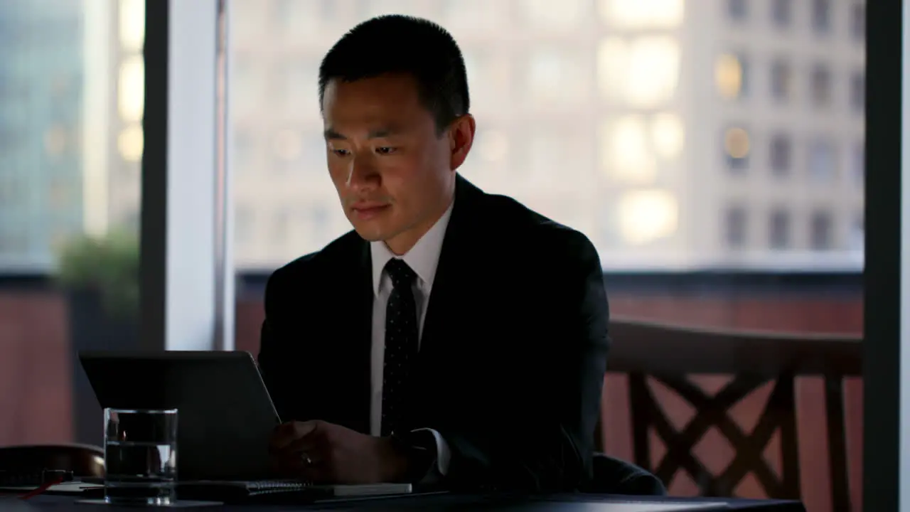 Front view of young Asian Businessman working on digital tablet in the modern hotel 4k