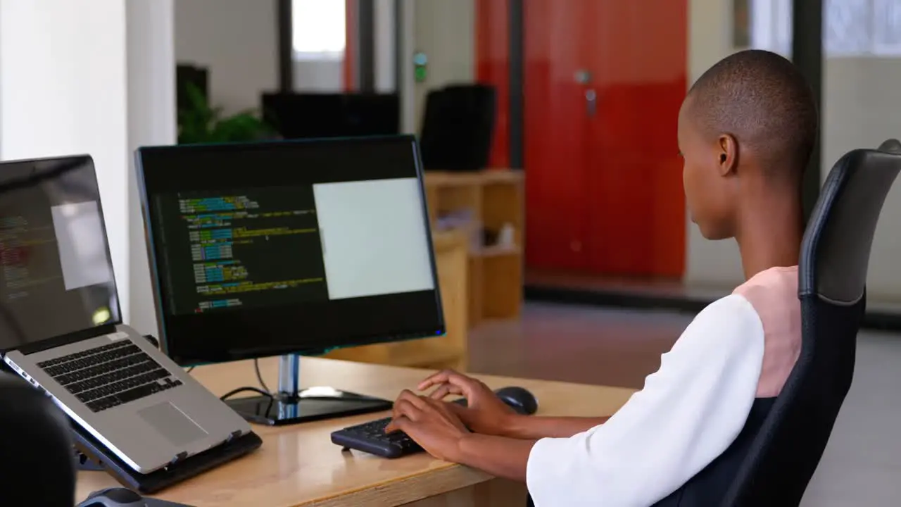 Side view of young black businesswoman working and sitting at desk in a modern office 4k