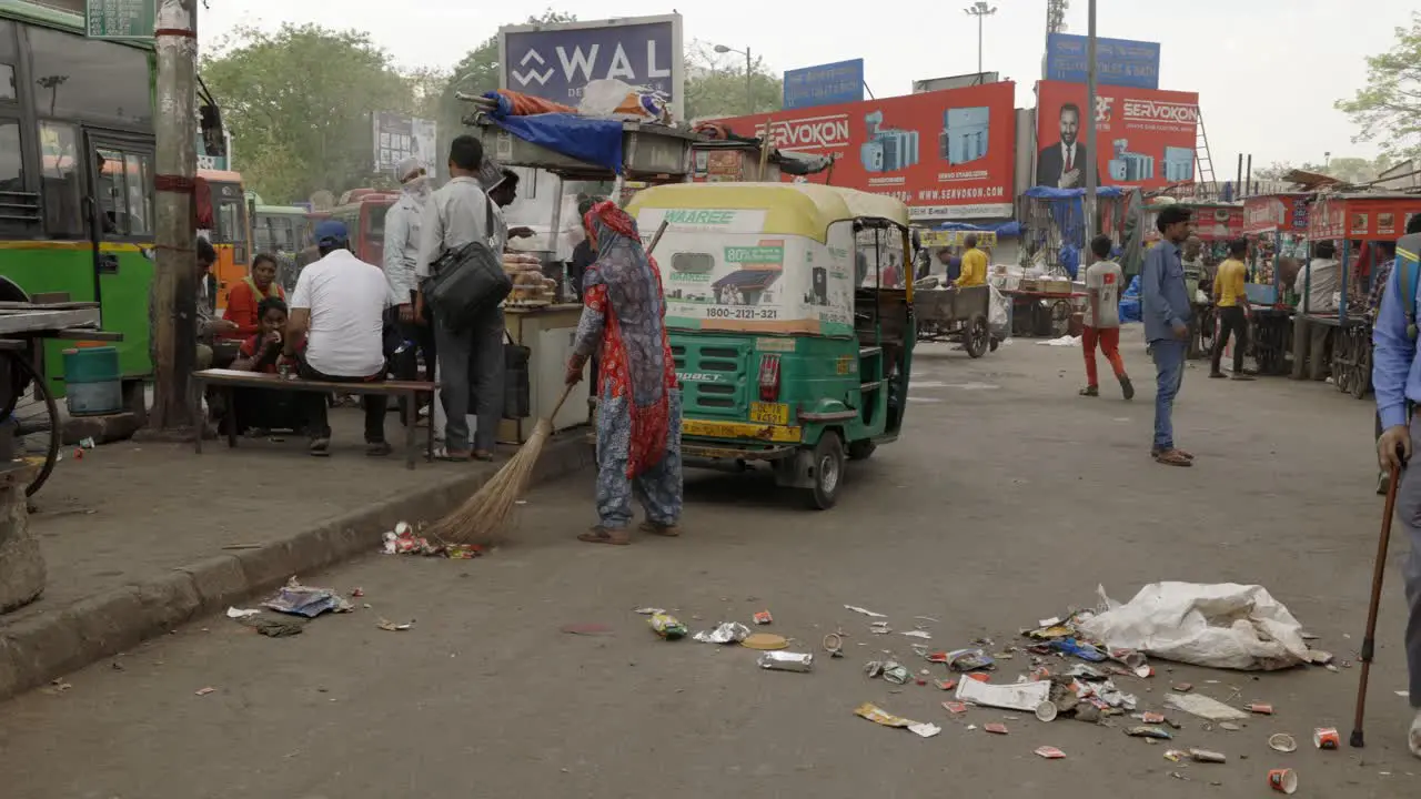 Woman brushing trash of street Delhi India