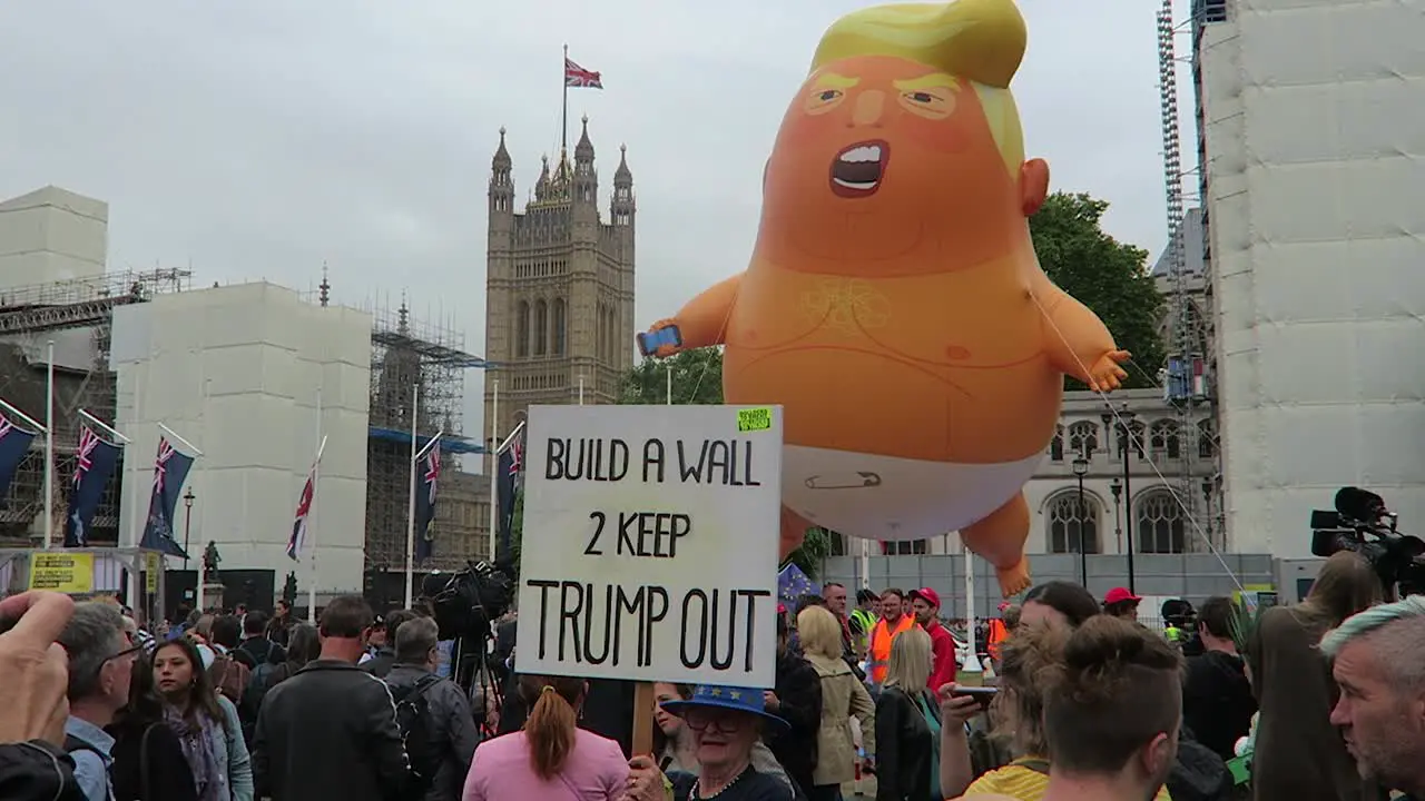 Adult female protester with placard against President Donald Trump with baby trump balloon in the background in Parliament Square Garden on 4th June 2019