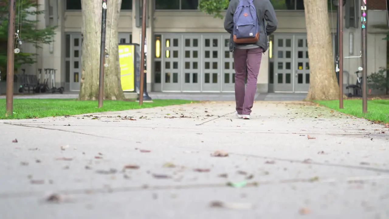 A young male walks across a college campus on a sunny summer day