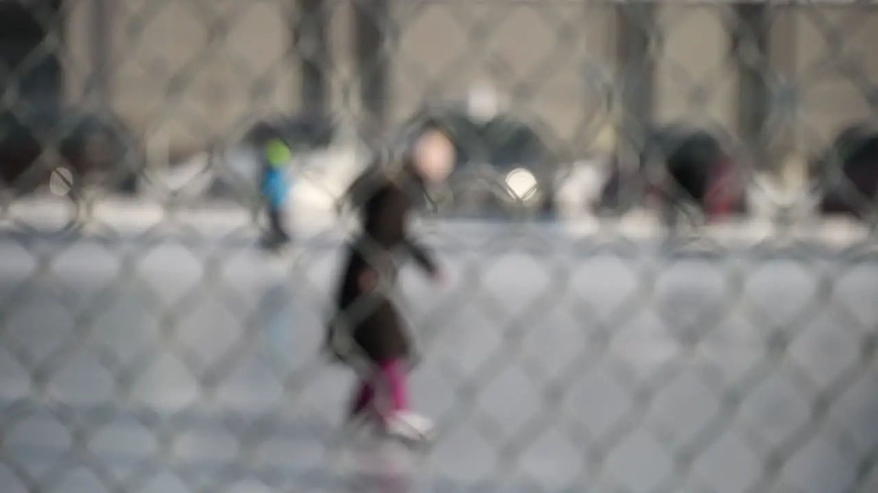 Abstract shot of people skating at an outdoor ice rink through a chain-link fence