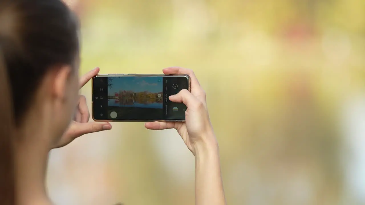 Young female taking photo of a lake