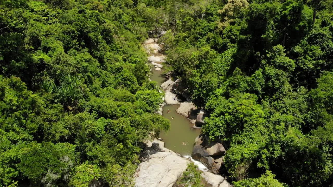 People swimming on a lake in rocks and waterfall with a road and ocean on the background