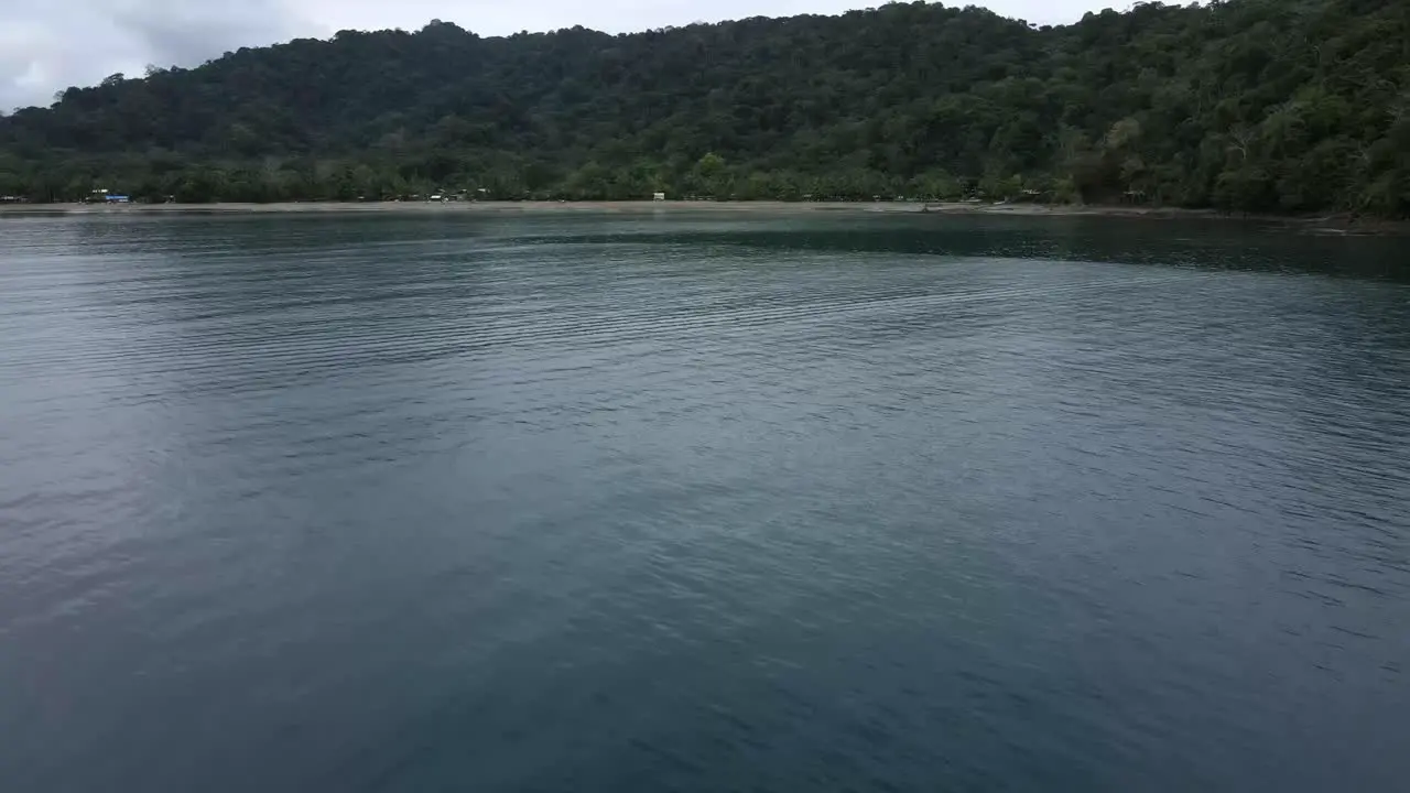 Drone shot of island Bahia Solano flying towards beach and rainforest