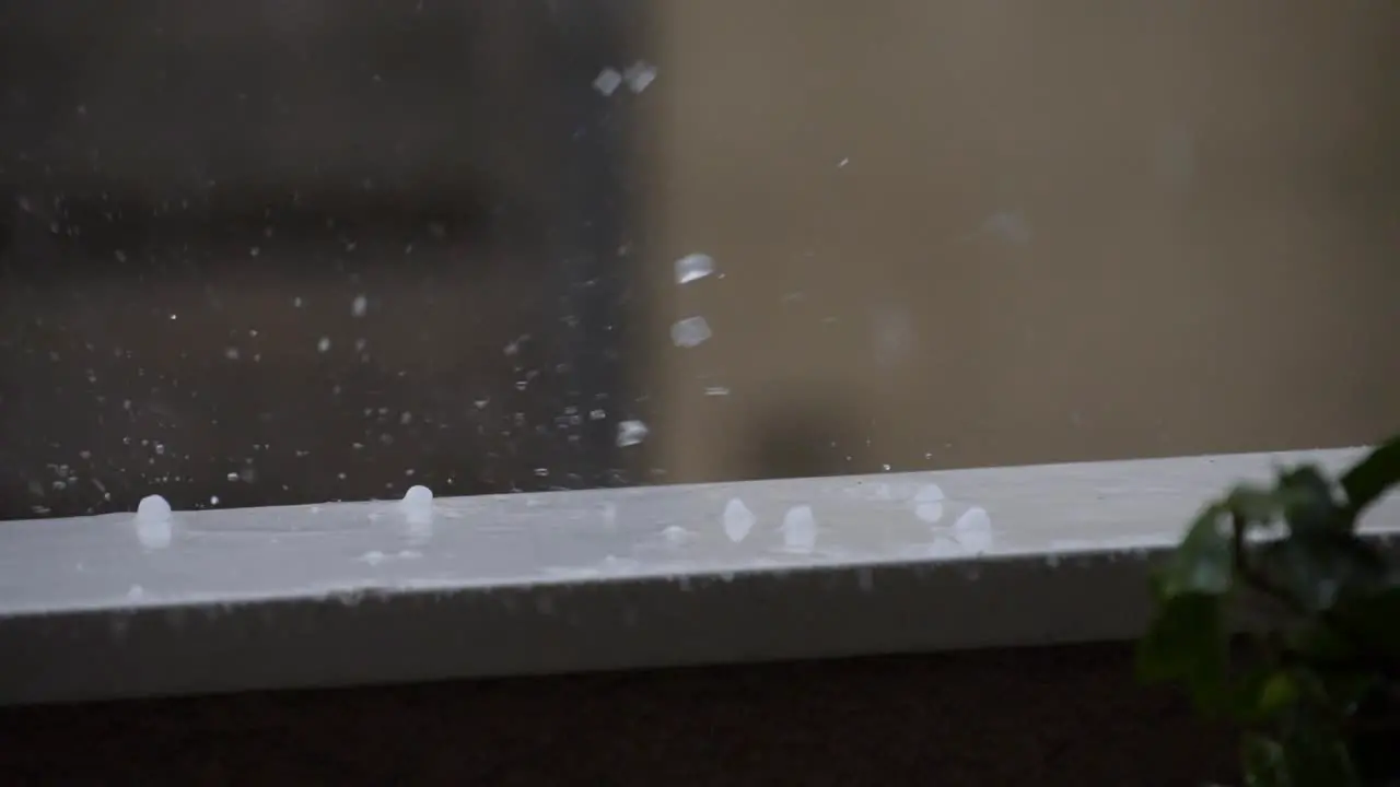 Hail drops splashing and rolling on a balcony railing during a storm at summer 180 fps slow motion