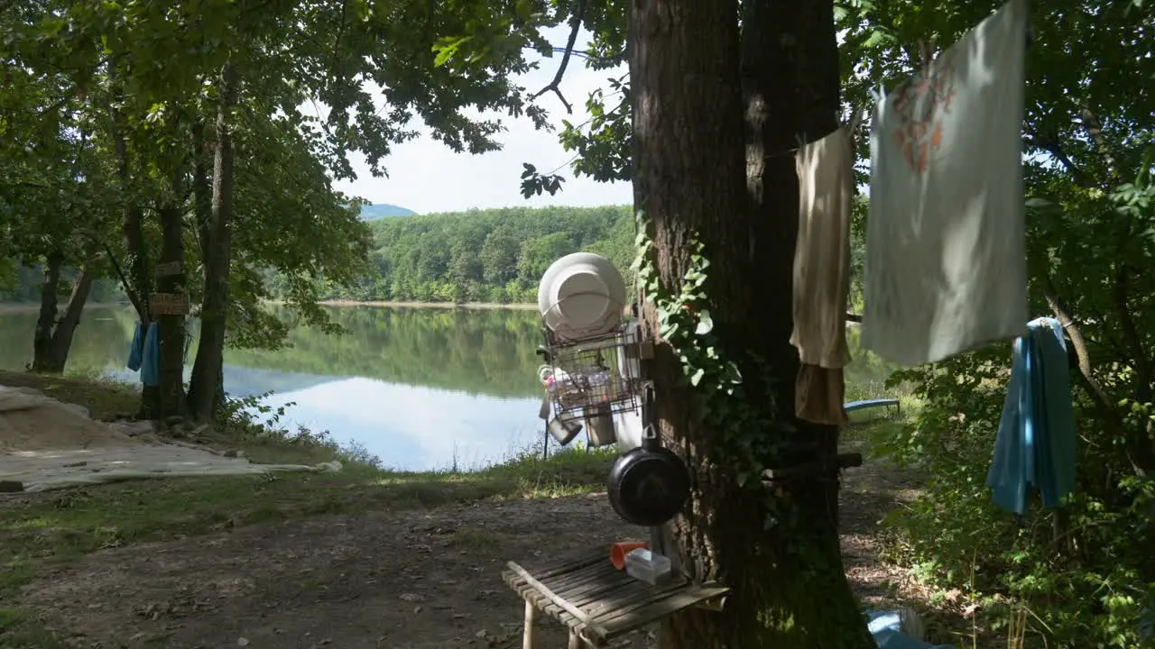 Off grid camping scene near to lake with personal items hung on trees