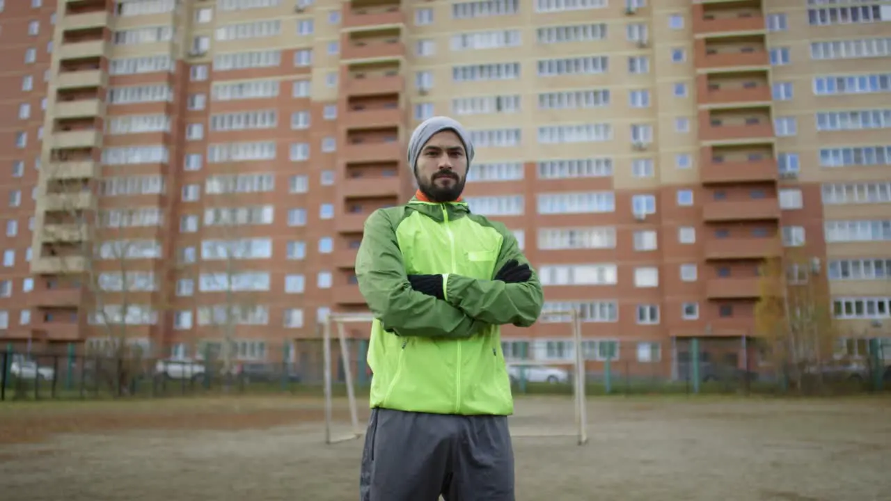 Confident Male Soccer Player Looking At Camera With Crossed Arms On The Field