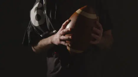 Close Up Studio Shot Of American Football Player Holding Ball With Low Key Lighting 2