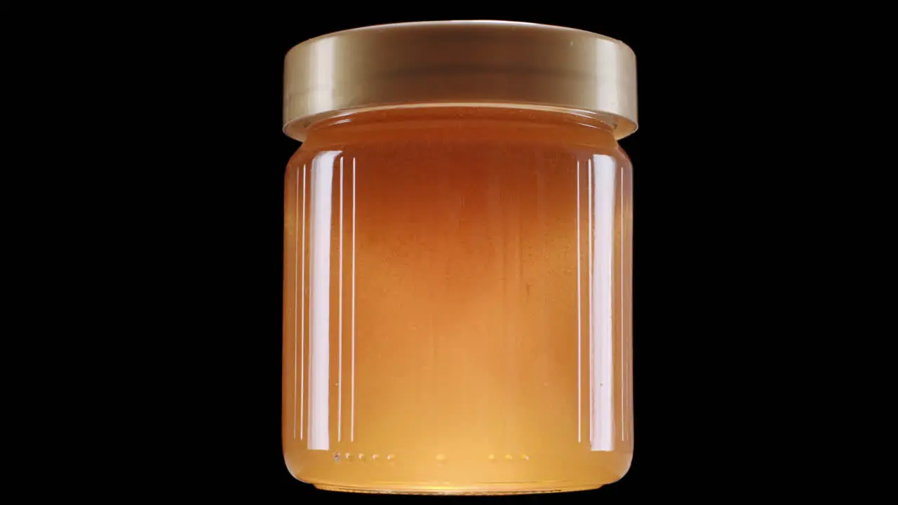 Glowing honey jar on black background static shot