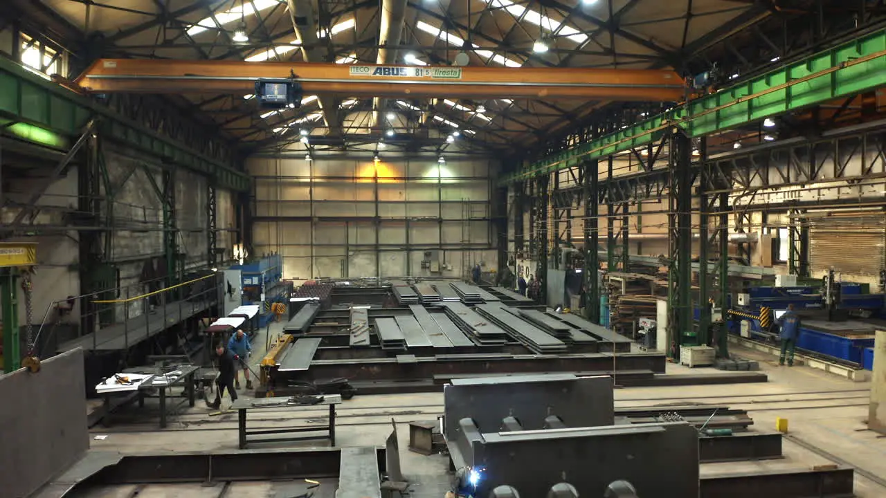 Steelworks factory storage hall with workers welding steel beams Brno