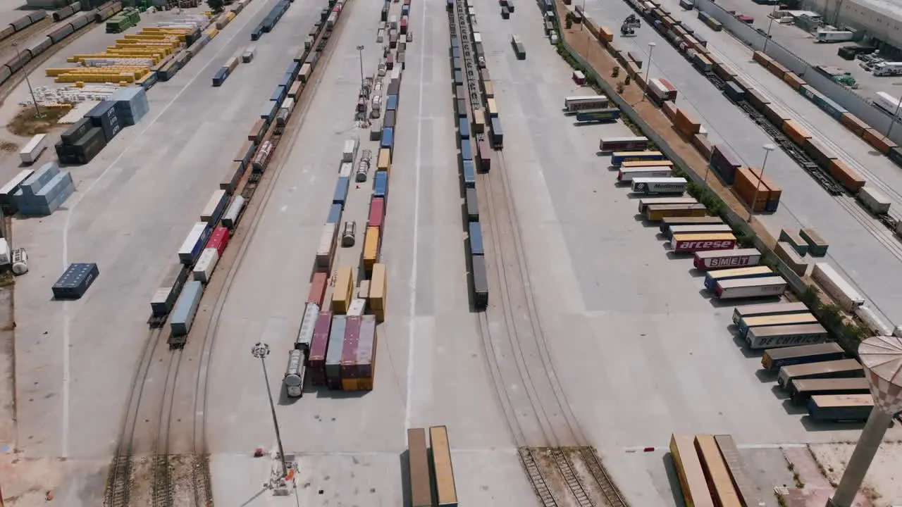 Slow aerial footage of shipping containers with trucks moving containers around