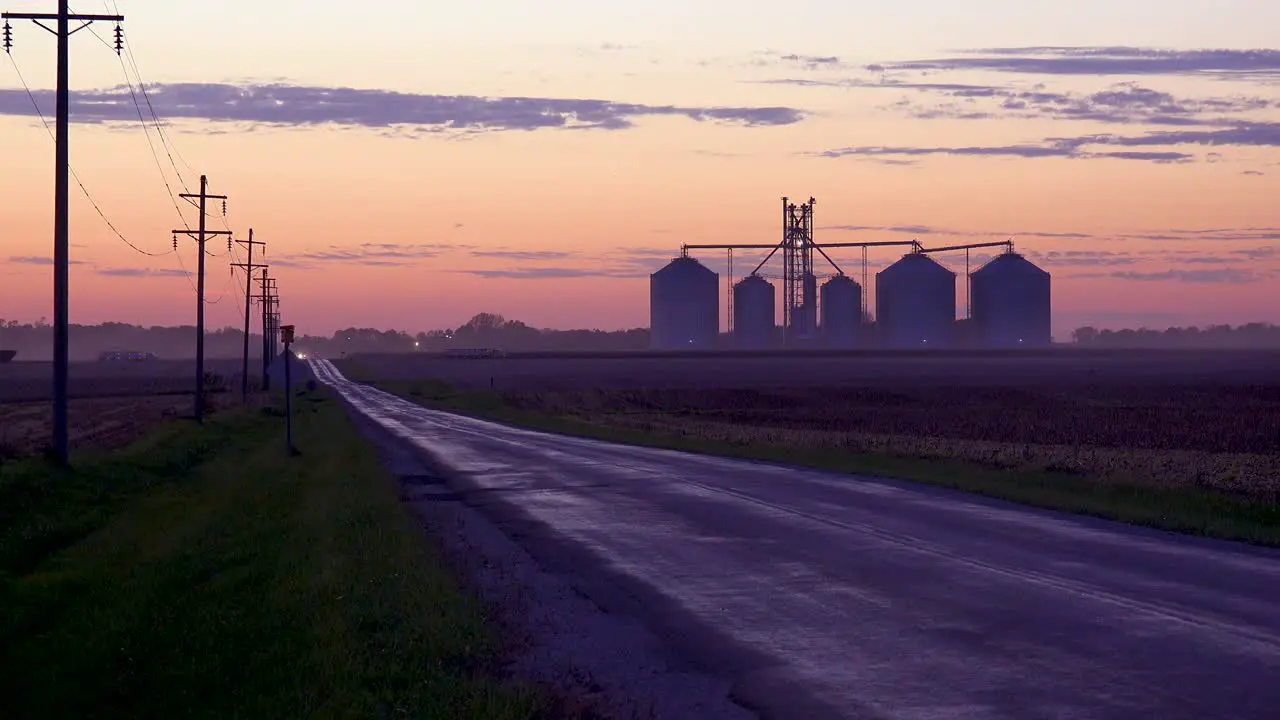 Grain Silos On A Large Commercial Farm Along A Country Road At Dusk In The Midwest