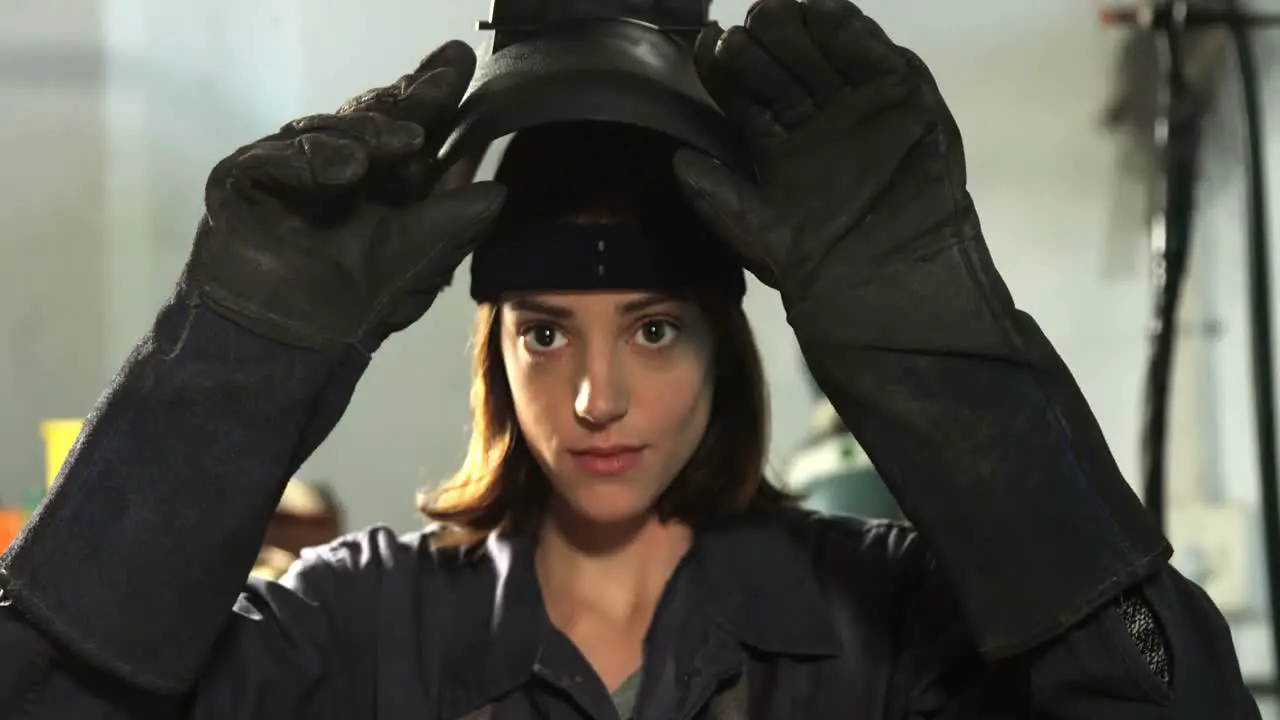 Female welder removing helmet