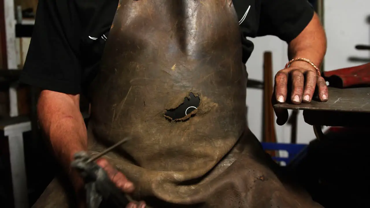 Mid-section of welder sitting with welding arch