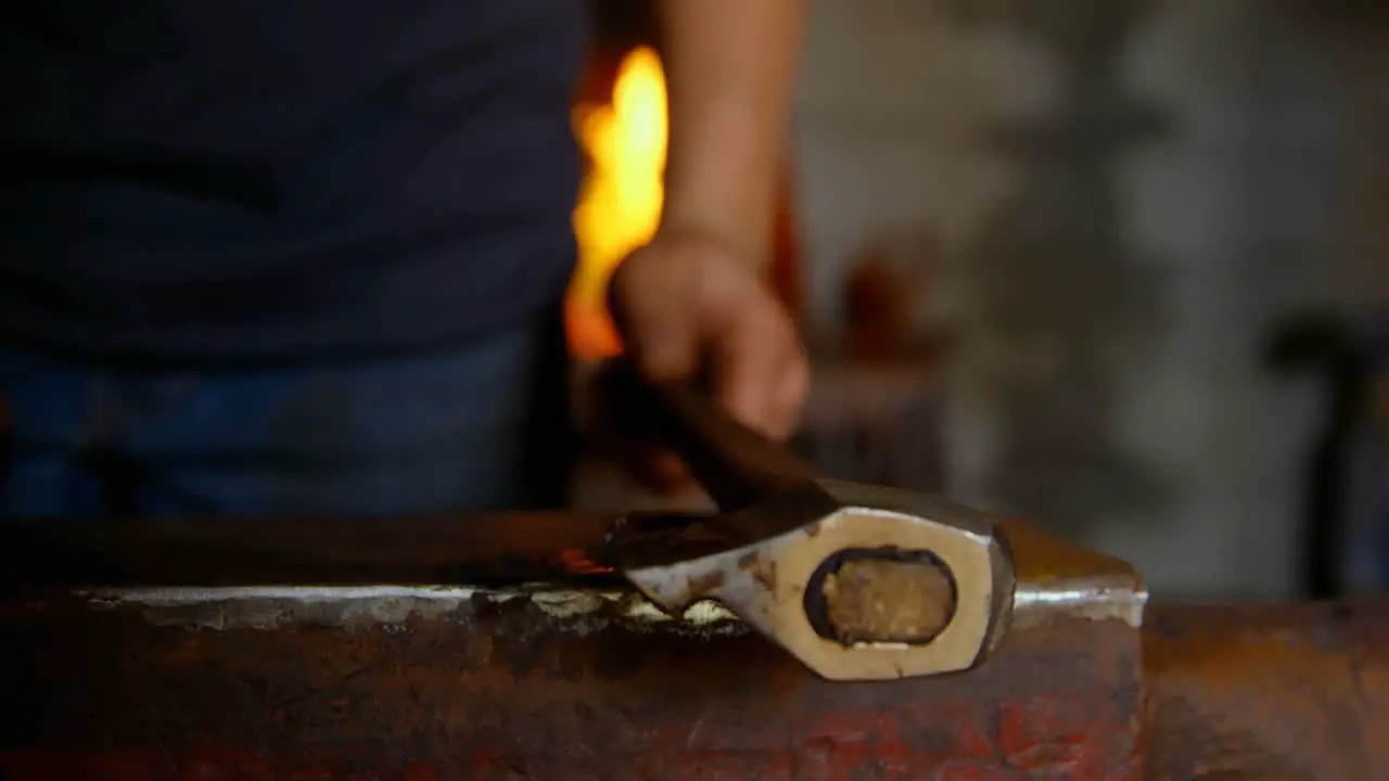 Metalsmith placing tool on anvil in factory