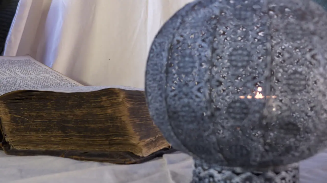 Historic old book open on table with flickering candle close up