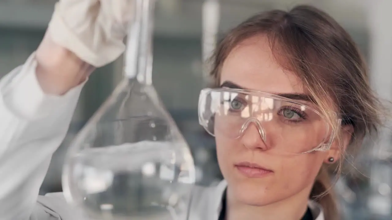 closeup portrait of female scientist examining liquid in test tube with magnifier