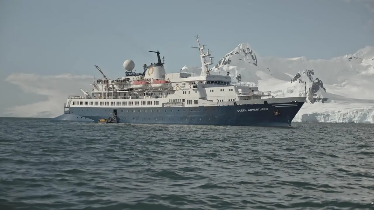 Big expedition ship in front of snow covered mountains and icebergs