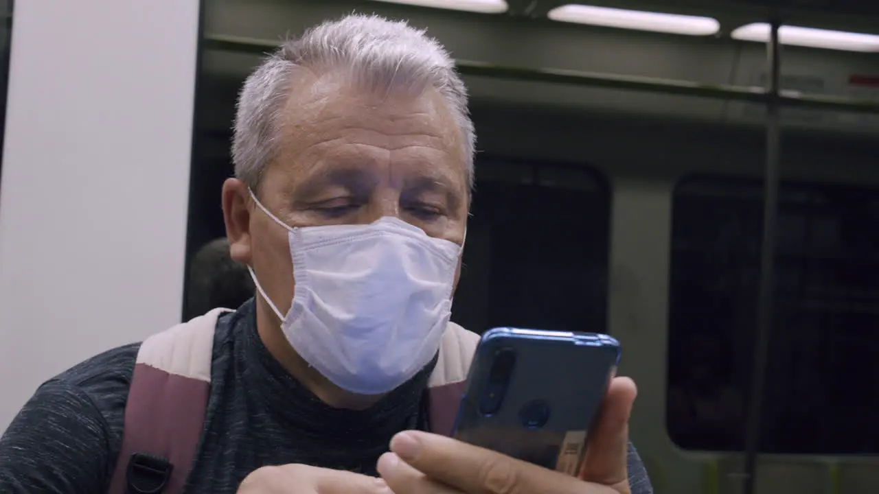 Senior commuter using mobile in subway