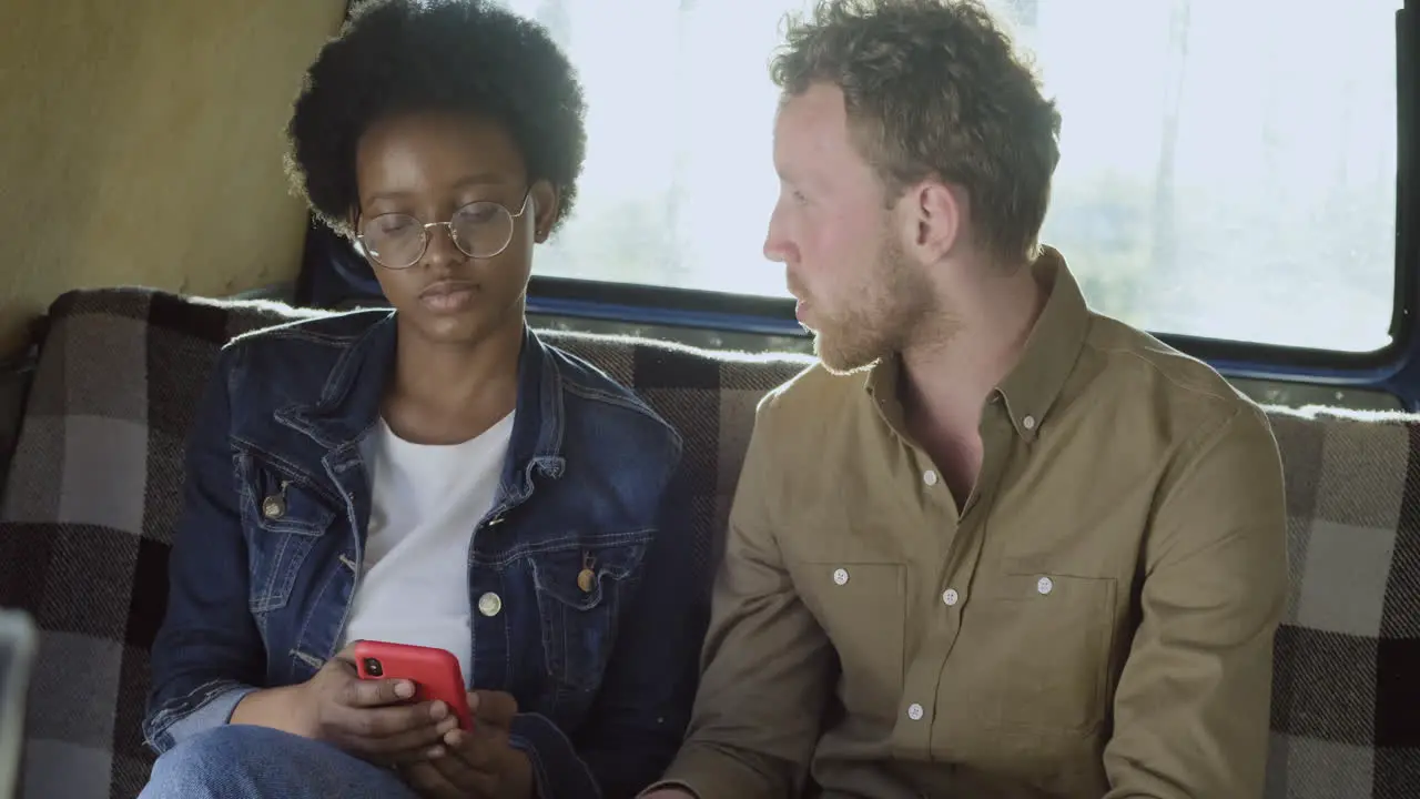 An Young Woman Talks With A Guy In A Caravan While Watching Her Cellphone 1