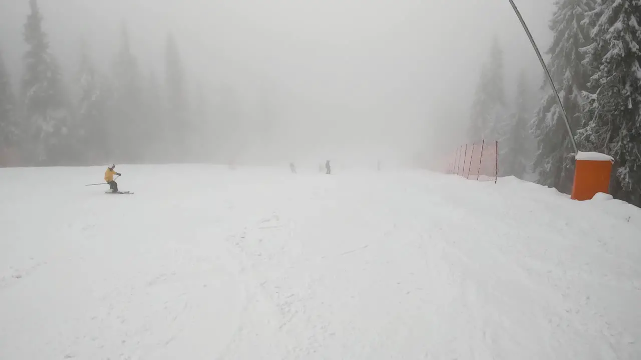 Skiers Skiing Down Misty Snow Covered Mountain