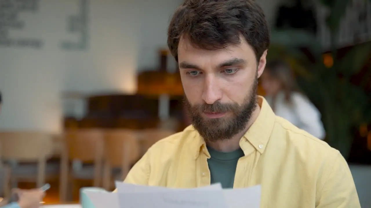 A Male Takes Notes In His Notebook In A Coffee Shop