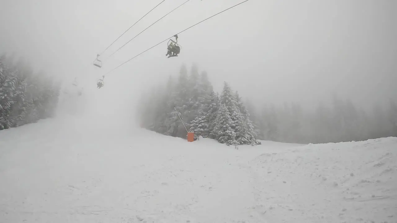 Ski Chair Lift Above Misty Snow Covered Mountain