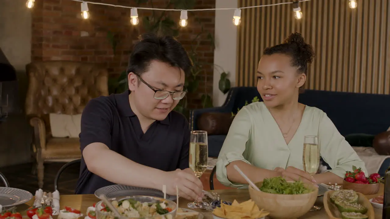 An Young Man And A Pretty Girl Toast Their Drinks Before A Meal