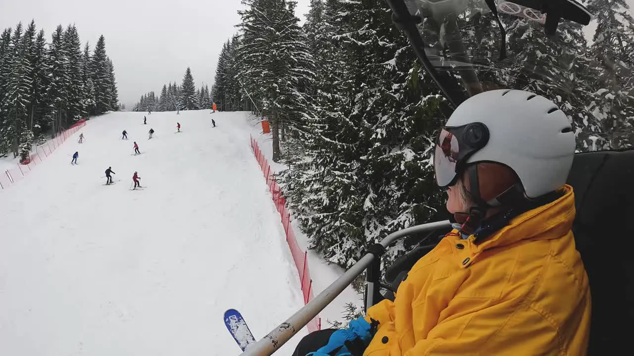 Skier On Chair Lift Across Snow Covered Mountain Below