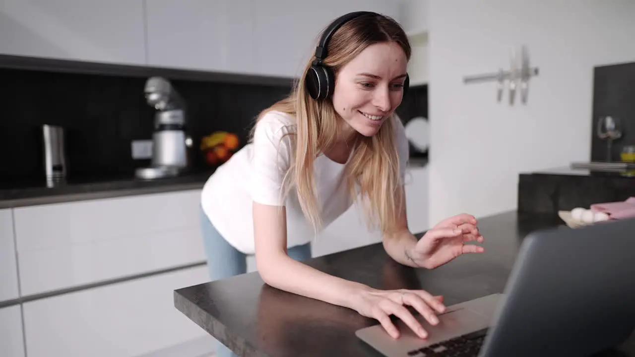 Woman Spending Time With Laptop Wearing Headphones In Kitchen