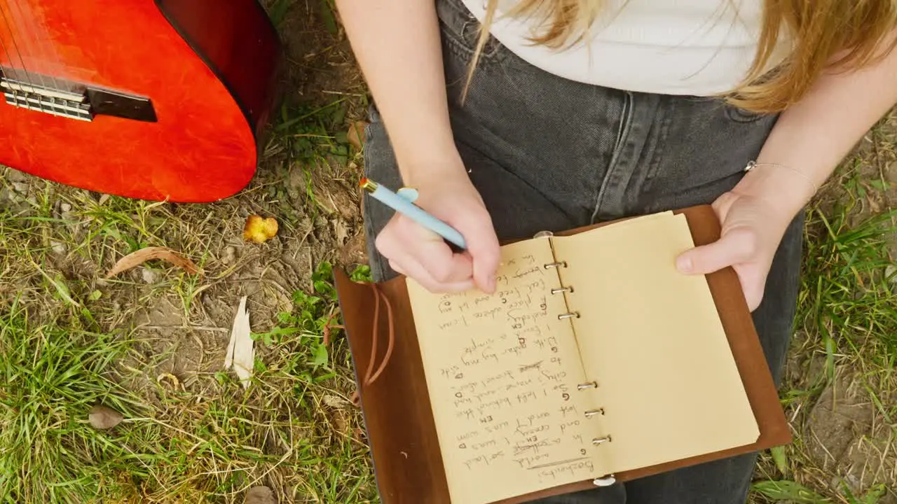 Female guitarist composer writes chords lyrics song book top down shot