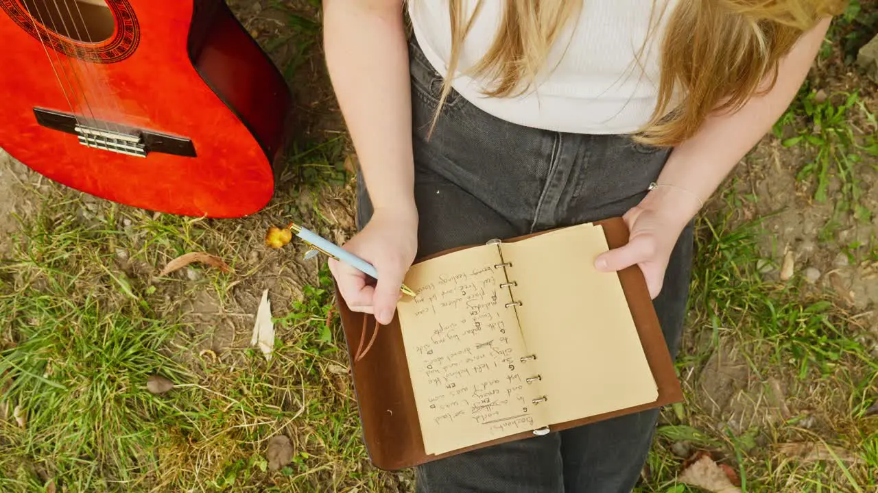 Young woman composer musician writes chords lyrics song book down shot