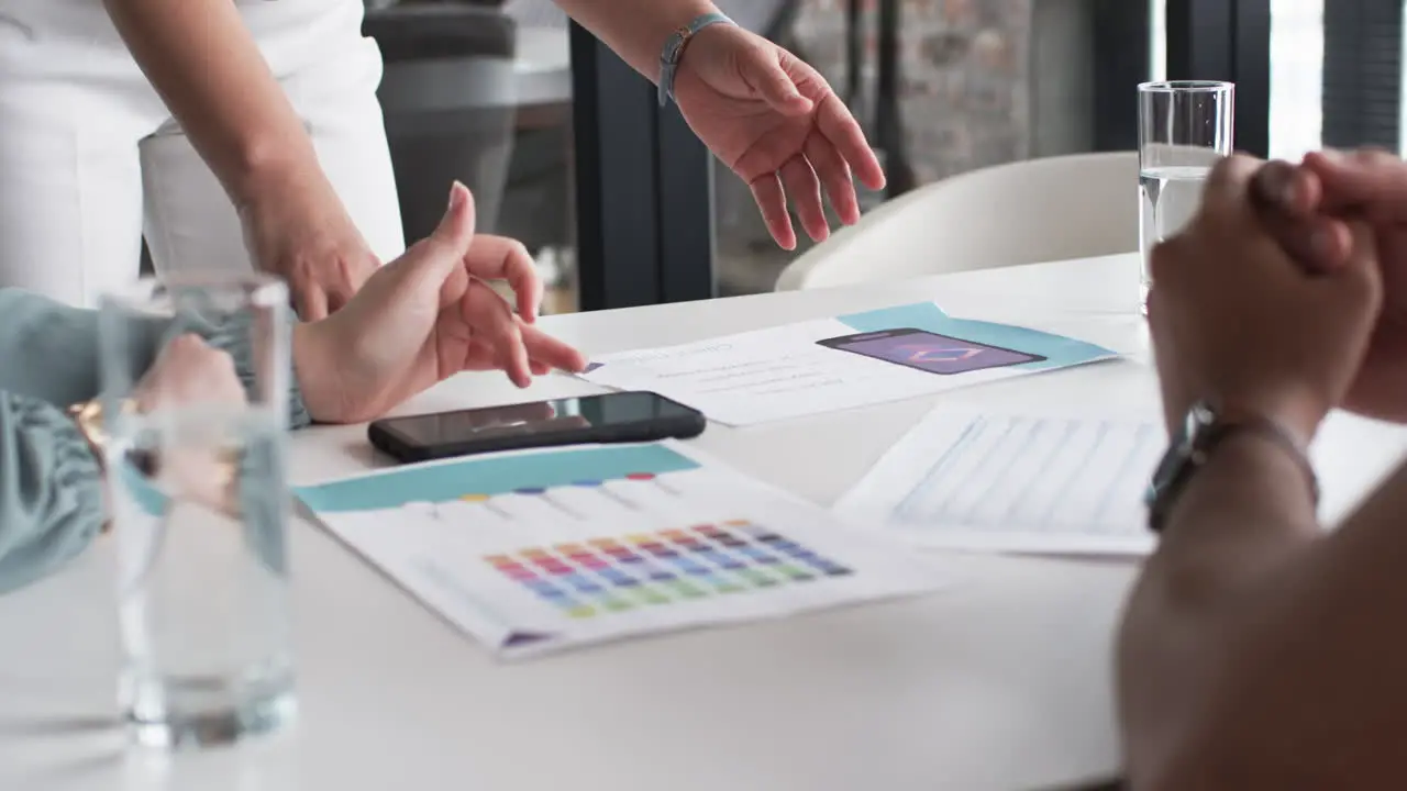 Hands gesture over a table with color swatches and a smartphone during a business creative brainstor