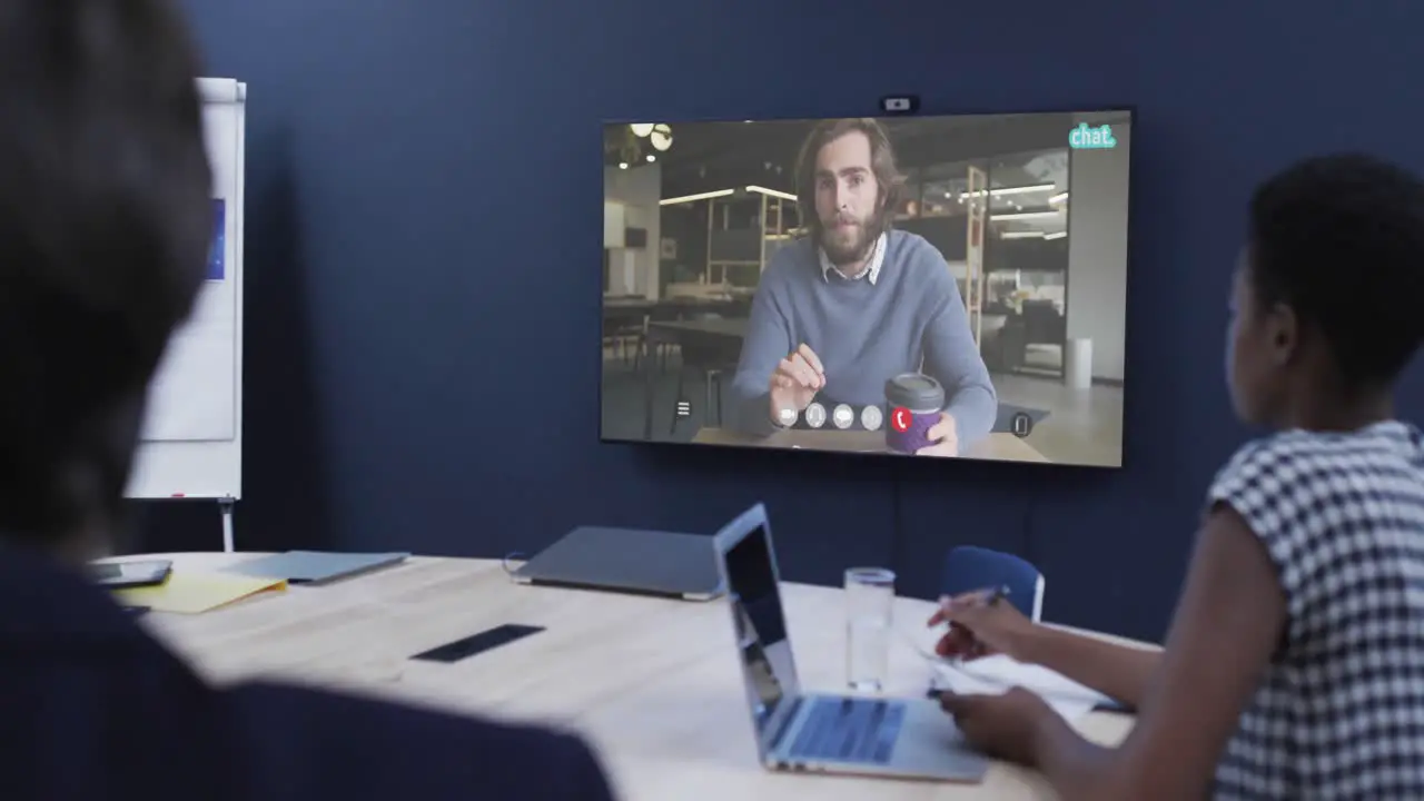 Diverse business people on video call with caucasian male colleague on tv screen