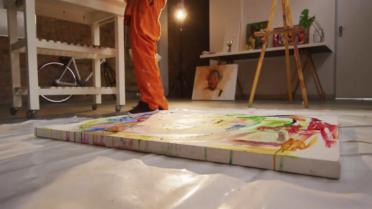 Low section of african american male artist pouring paint on canvas at art studio